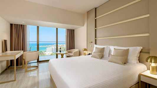 Moderni hotellihuone, jossa suuri sänky ja näkymä merelle. (Tekoälyn luoma teksti)