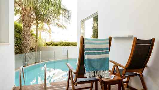 Kaksi aurinkotuolia pienen uima-altaan äärellä. (Tekoälyn luoma teksti)