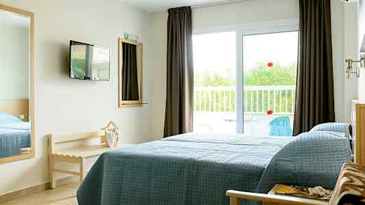 Hotellihuone, jossa on sänky lasioven vieressä, joka johtaa parvekkeelle. (Tekoälyn luoma teksti)