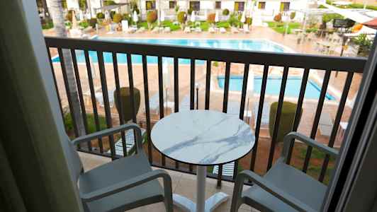 Kaksi tuolia ja pöytä parvekkeella, näkymä uima-altaaseen ja ympäröiviin rakennuksiin. (Tekoälyn luoma teksti)