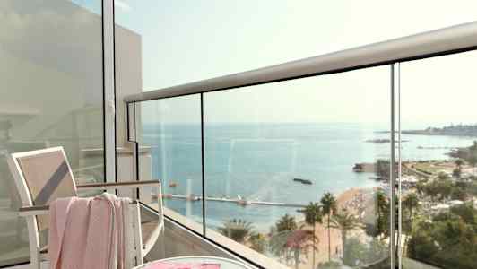 Näkymä parvekkeelta merelle, mukana tuoli, pöytä ja aikakauslehti. (Tekoälyn luoma teksti)