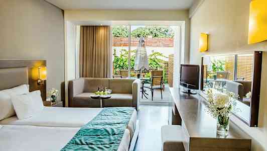 Hotellihuone, jossa on sänky, istuinryhmä ja pääsy terassille. (Tekoälyn luoma teksti)