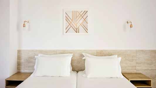 Kaksi erillistä sänkyä, joissa on valkoiset vuodevaatteet, puinen pääty ja moderne seinäkoriste yläpuolella. (Tekoälyn luoma teksti)