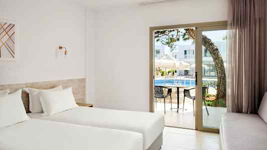 Hotellihuone, jossa kaksi erillistä vuodetta, näkymä altaalle lasiovien läpi. (Tekoälyn luoma teksti)