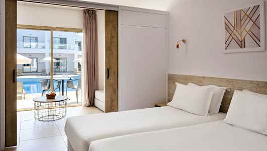 Hotellihuone, jossa kaksi yhden hengen vuodetta ja näkymä ulkouima-altaalle ja aurinkotuoleille. (Tekoälyn luoma teksti)