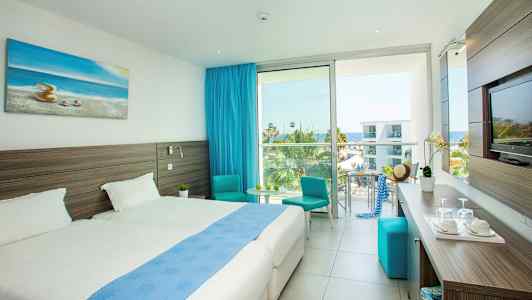 Nykyaikainen hotellihuone, jossa on parivuoteita, merinäköala ja sininen sisustus. (Tekoälyn luoma teksti)