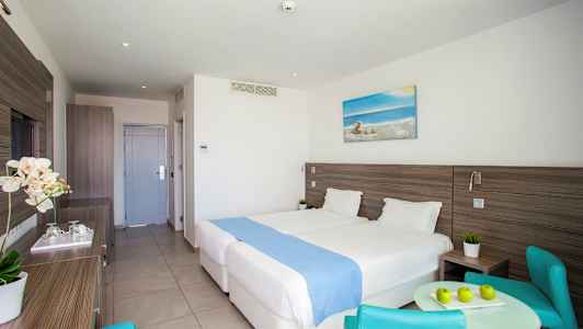 Hotellihuone, jossa kaksi sänkyä, pöytä ja tuolit. (Tekoälyn luoma teksti)