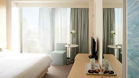 Hotellihuone, jossa sänky, pöytä, tuoli ja peili. (Tekoälyn luoma teksti)