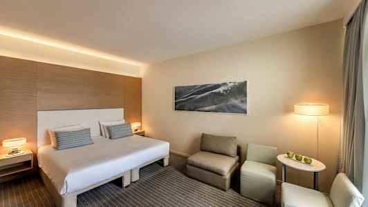 Hotellihuone, jossa parivuode, istumapaikka ja pöytä. (Tekoälyn luoma teksti)