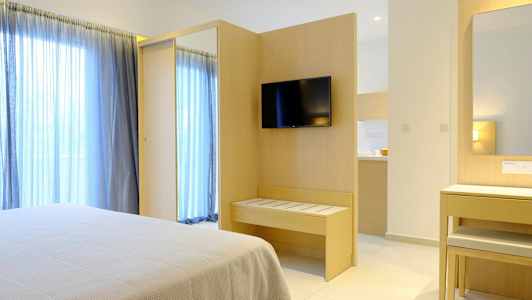 Hotellihuone, jossa sänky, TV seinällä ja peili kirjoituspöydän äärellä. (Tekoälyn luoma teksti)