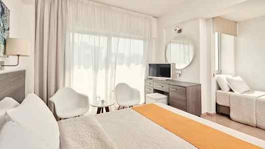 Valoisa ja moderni hotellihuone, jossa on sänky, oleskelutila ja työpöytä. (Tekoälyn luoma teksti)