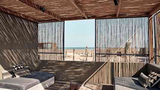 Avoin terassi, jolla on sohvia, katto ja seinät ovat puusta, ja näkymä merelle. (Tekoälyn luoma teksti)