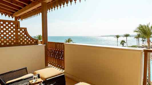 Parveke, jossa on rottinkikalusteet ja näkymä merelle sekä palmuja. (Tekoälyn luoma teksti)