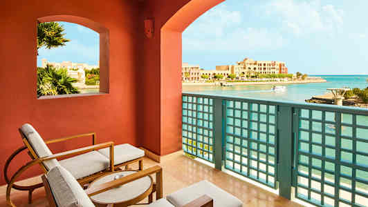 Näkymä parvekkeelta, jossa on istuimia, rannikkoalueelle ja rakennuksiin. (Tekoälyn luoma teksti)