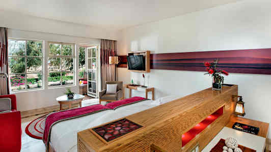 Hotellihuone, jossa on nykyaikainen sisustus ja suuret ikkunat puutarhaan. (Tekoälyn luoma teksti)