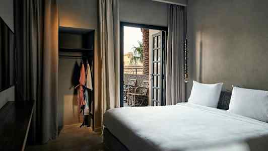 Hotellihuone, jossa sänky, parveke ja vaatekaappi. (Tekoälyn luoma teksti)