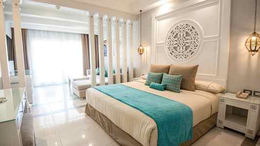 Tyylikäs hotellihuone, jossa on suuri sänky, koristeelliset yksityiskohdat ja pehmeät värit. (Tekoälyn luoma teksti)