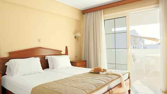 Hotellihuone, jossa on parivuode, vaaleat verhot ja parveke ulkokalusteilla. (Tekoälyn luoma teksti)