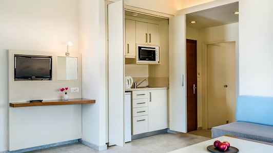 Hotellihuone, jossa on pieni keittiö ja olohuoneen sisustus. (Tekoälyn luoma teksti)