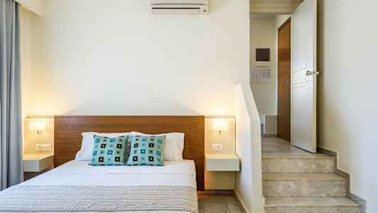 Sisäkuva makuuhuoneesta, jossa on parivuode, moderni sisustus ja portaat lähellä vuodetta. (Tekoälyn luoma teksti)