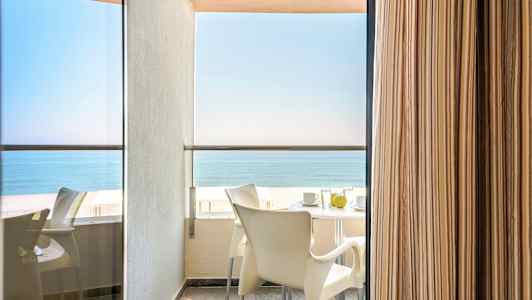 Parvekkeen näkymä, pöytä ja tuolit sekä meri taustalla. (Tekoälyn luoma teksti)