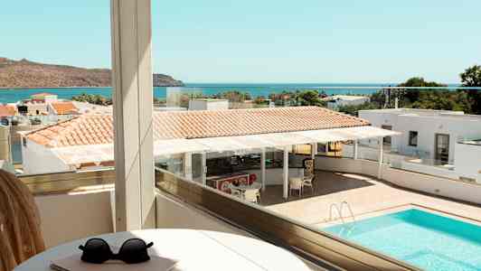 Näkymä parvekkeelta uima-altaalle, osia hotellialueesta ja meri taustalla. (Tekoälyn luoma teksti)