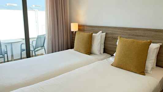 Kuva hotellihuoneesta, jossa on kaksi erillistä vuodetta ja parveke. (Tekoälyn luoma teksti)