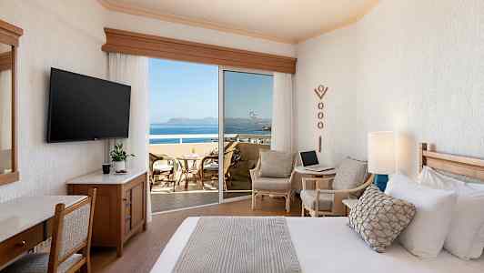 Hotellihuone, jossa on sänky, istuinryhmä ja parveke merinäköalalla. (Tekoälyn luoma teksti)