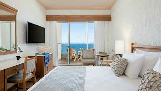 Hotellihuone, josta on näkymä merelle suurten lasiovien kautta. (Tekoälyn luoma teksti)