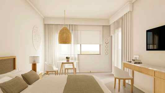 Valoisa hotellihuone, jossa on suuri sänky, roikkuva lampunvarjostin, pöytä ja kaksi tuolia sekä seinälle kiinnitetty televisio. (Tekoälyn luoma teksti)