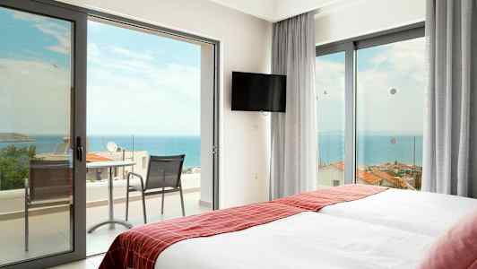 Hotellihuone, jossa kaksi sänkyä ja ovet parvekkeelle, josta näkymä merelle. (Tekoälyn luoma teksti)