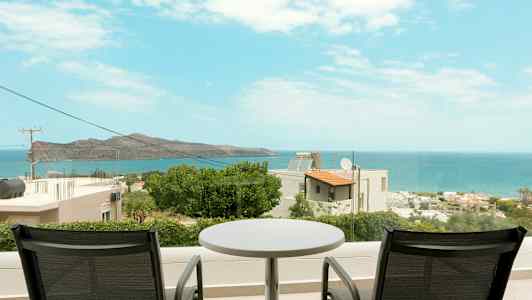 Kaksi tuolia ja pöytä parvekkeella, josta on näkymä merelle ja rannikkoalueelle. (Tekoälyn luoma teksti)