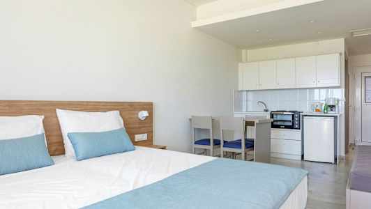 Hotellihuone, jossa on sänky ja pieni keittiötila. (Tekoälyn luoma teksti)