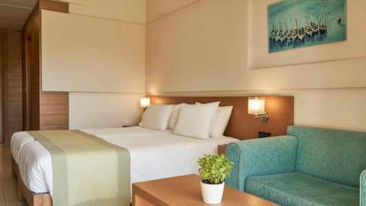 Hotellihuone, jossa on parivuode, vihreä sohva ja seinäkoriste. (Tekoälyn luoma teksti)