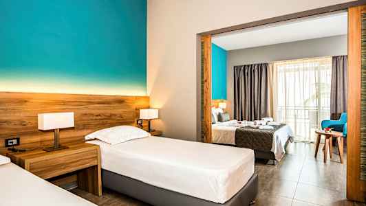 Hotellihuone, jossa kaksi yhden hengen vuodetta ja näkymä parivuoteeseen avoimen portaikon kautta. (Tekoälyn luoma teksti)