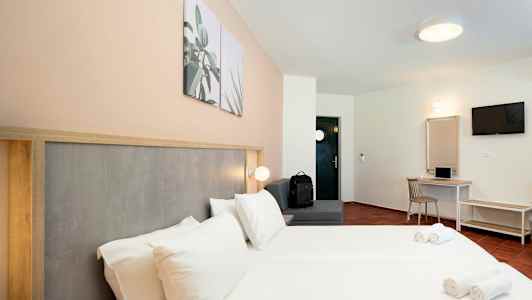 Hotellihuone, jossa parivuode, istuinalue, työpöytä ja TV. (Tekoälyn luoma teksti)