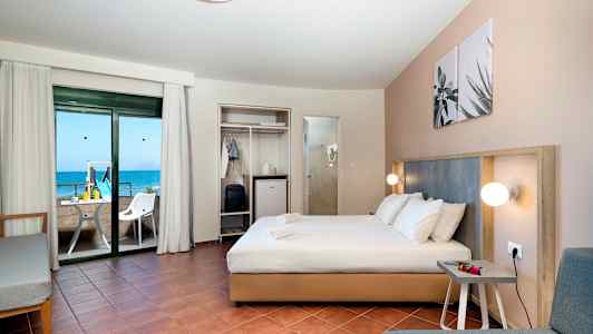 Hotellihuone jossa on parivuode, istuinryhmä ja parveke merinäköalalla. (Tekoälyn luoma teksti)