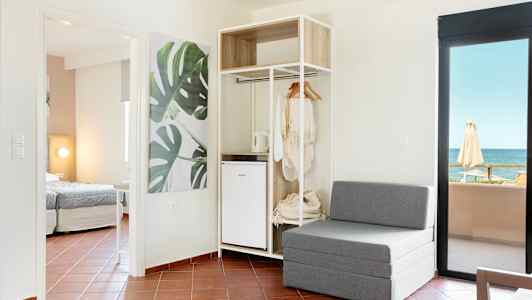 Moderni hotellihuone, jossa istuimet, avoin vaatekaappi ja merinäköala. (Tekoälyn luoma teksti)