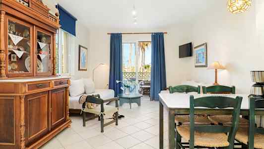 Vaalea olohuone, jossa sohvia, ruokapöytä ja tuoleja sekä suuret ikkunat sinisillä verhoilla. (Tekoälyn luoma teksti)