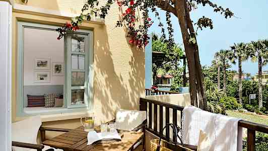 Parveke puutarhanäkymällä, pöytä ja tuolit sekä vesikannu ja lasit. (Tekoälyn luoma teksti)