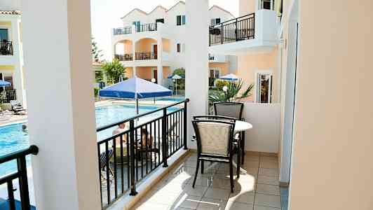 Parveke, jossa on kalusteet, näkymä altaalle ja oransseja rakennuksia. (Tekoälyn luoma teksti)