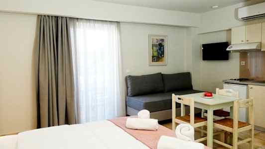 Hotellihuone, jossa on sänky, sohva, ruokapöytä tuoleilla ja minikeittiö. (Tekoälyn luoma teksti)