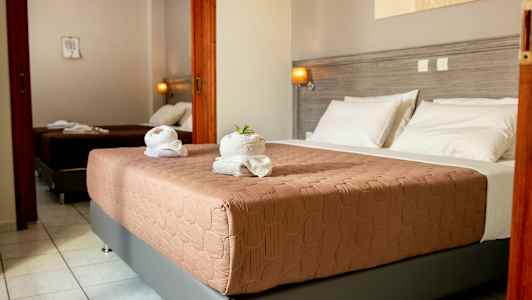 Hotellihuone, jossa kaksi sänkyä, vaaleanharmaat seinät ja valkoinen vuodevaatteet. (Tekoälyn luoma teksti)