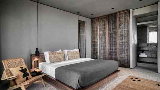 Moderni makuuhuoneen sisustus, jossa on suuri sänky ja nojatuoli. (Tekoälyn luoma teksti)