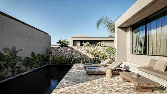 Moderni ulkotila, jossa kivipohjainen uima-allas, aurinkotuoleja ja kasveja ympärillä. (Tekoälyn luoma teksti)