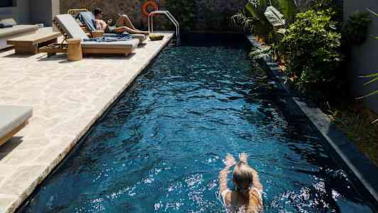 Henkilö ui altaassa, vierellä aurinkotuoleja. (Tekoälyn luoma teksti)