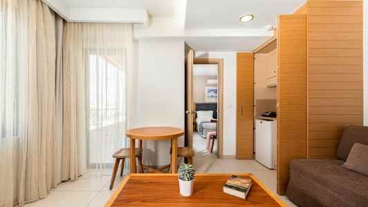 Hotellihuone, jossa on yksinkertainen sisustus, tummat huonekalut ja suuret ikkunat. (Tekoälyn luoma teksti)