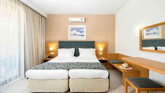 Standardihuone, jossa kaksi erillistä sänkyä, seinävalaisin ja peili. (Tekoälyn luoma teksti)