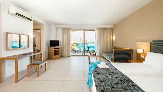 Hotellihuone, jossa on parivuode, istuimet, televisio ja parveke näkymällä. (Tekoälyn luoma teksti)