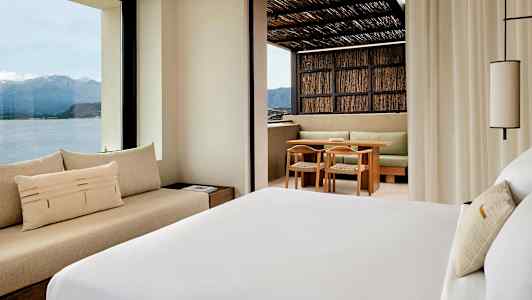 Hotellihuone, josta on näkymä vuorille ja merelle sekä terassi, jossa istuma-alue. (Tekoälyn luoma teksti)